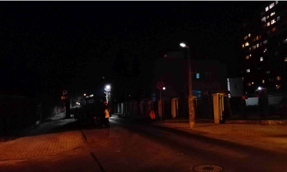 Ulica PCK w Toruniu. Na zdjęciu skrzyżowanie oświetlone ciepłym światłem z ulicy Dekerta, gdzie jeszcze w użyciu są lampy sodowe. Lampa LED “świeci”, ale nie działa. Piesi (tak, są na tym zdjęciu) stają się widoczni dopiero w świetle reflektorów samochodowych Fot. Anna Zglińska